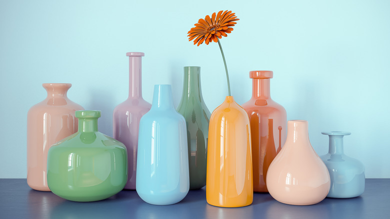 Several vases on a shelf in pale pastel colors.