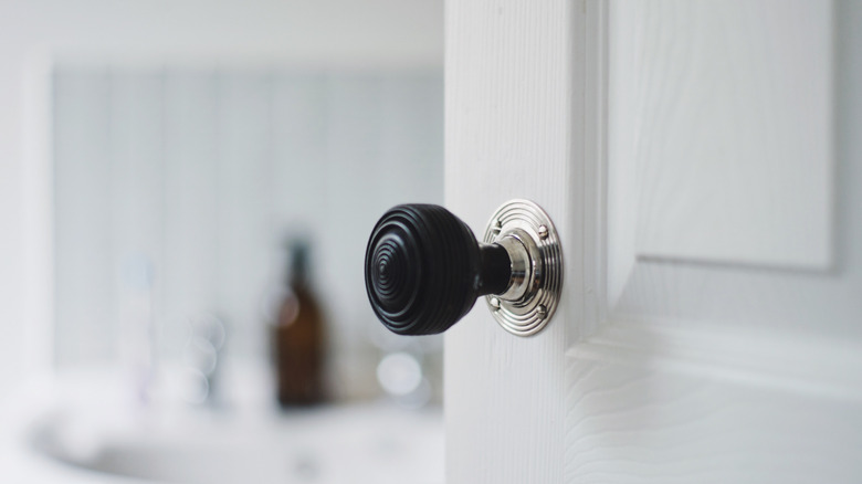 A basic black doorknob on a white door