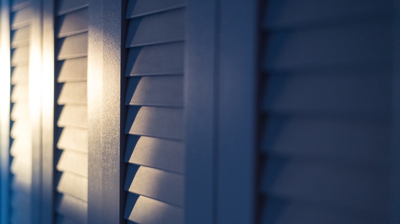 This is a shadowy picture of sunlight hitting louvered closet doors in an ominous way.