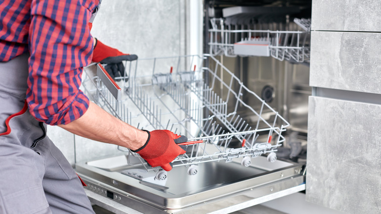 Person wearing gloves removing the rack from dishwasher