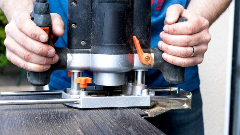 Man holding plunge router on gray wood door