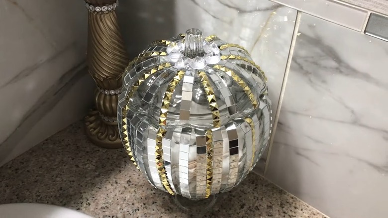 Disco ball pedestal vase sitting on bathroom counter.