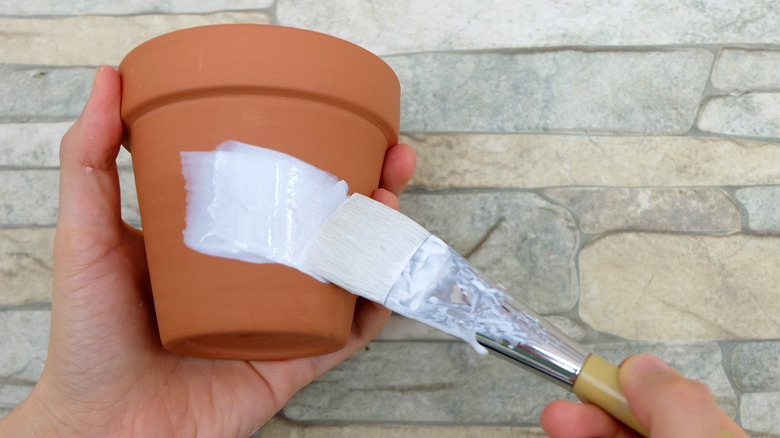 Hand painting a terra cotta planter white with paintbrush