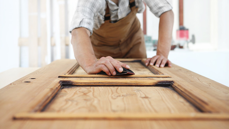 A man sanding a wood interior door