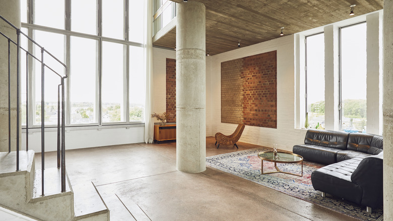 An austere living room with a cylindrical concrete pillar in the center