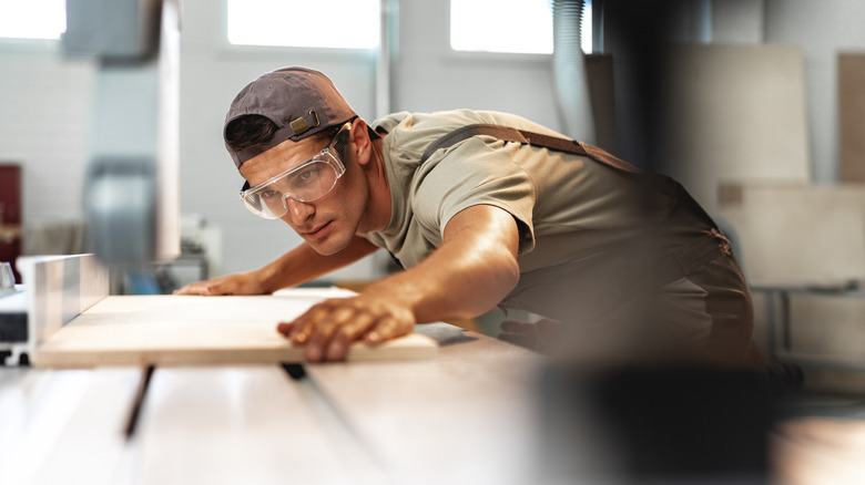 Person cutting a panel of wood with a table saw