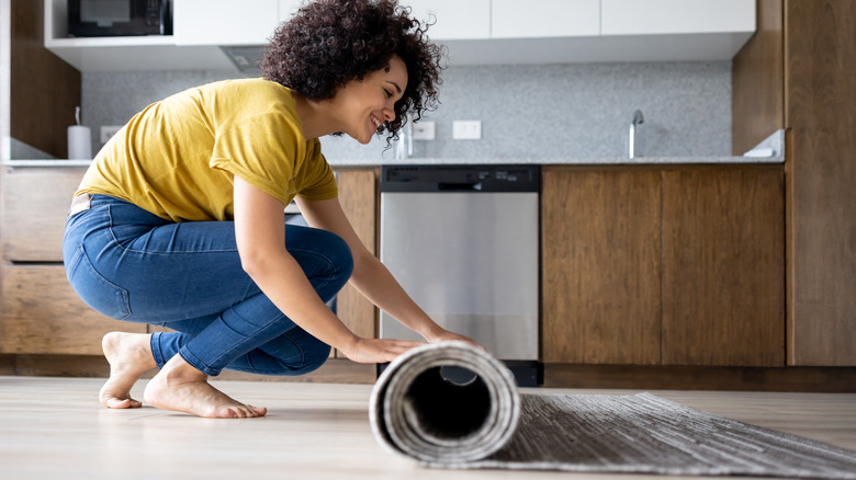 woman rolling up area rug