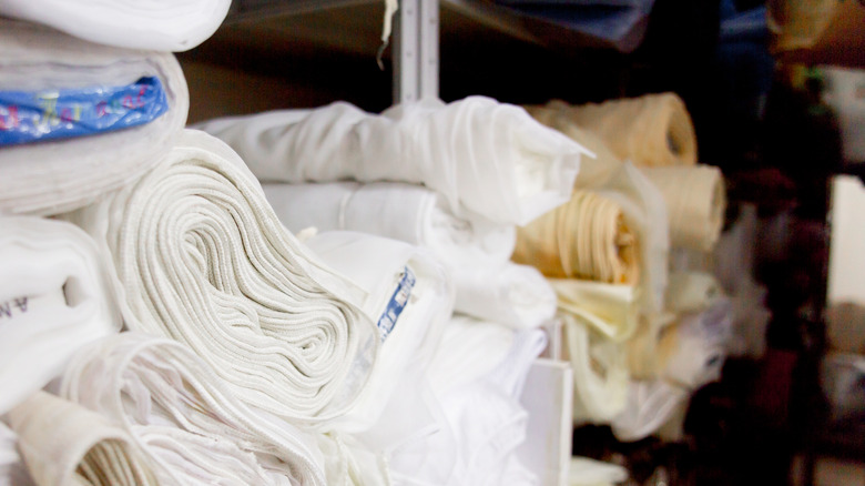 Bolts of fabric of various colors sit on a shelf in a fabric store.