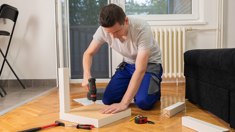 A man takes apart a small LACK side table so he can renovate it.