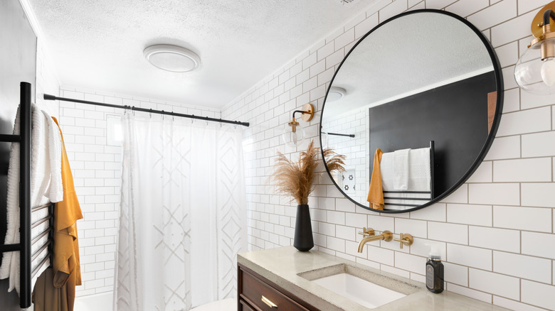 Bathroom with a stylish round mirror and sconce lights
