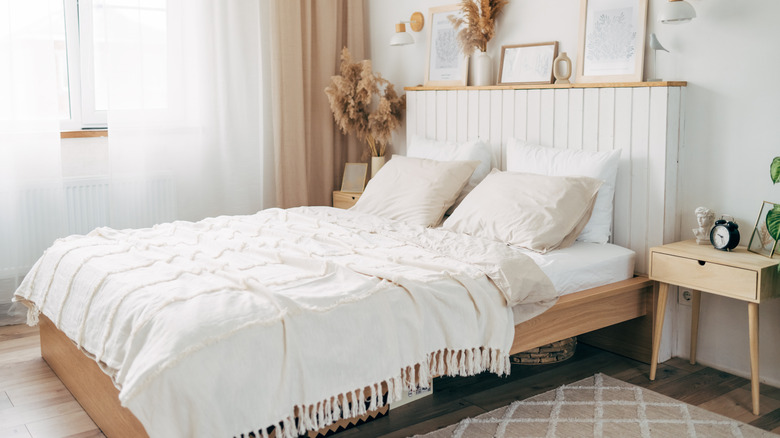 Stylish bedroom during daytime with wooden bed and white bedding