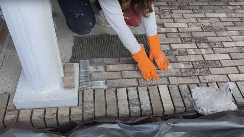 Woman installing brick veneers over concrete patio