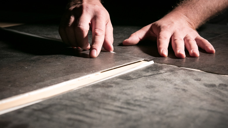 Hands laying tiles on floor