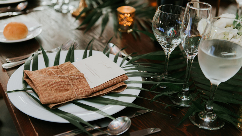 Table setting with palm leaf under napkin on a plate