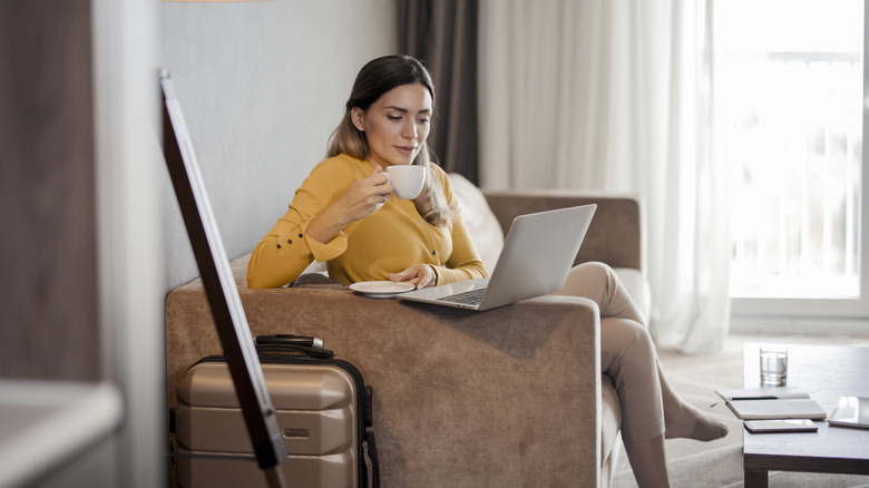 Woman on couch with computer and coffee.