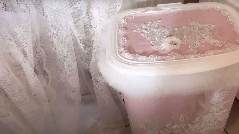 A laundry hamper decorated with pink fabric and tulle