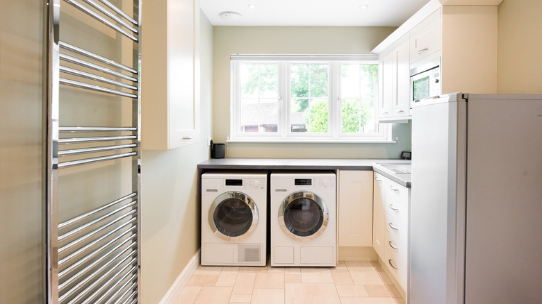 A laundry room has a washer dryer by a sunny window