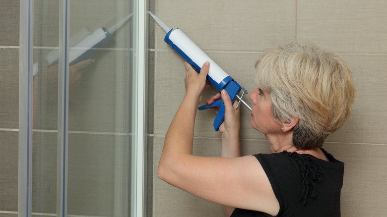 Woman sealing shower tile