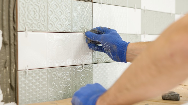 Man installing ceramic kitchen backsplash