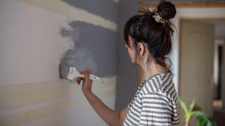 Woman painting taped wall gray