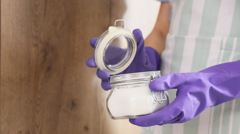 A person is opening a jar of baking soda to use as a cleaning ingredient