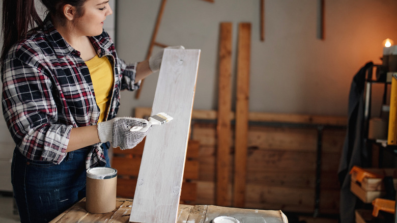 Woman painting piece of wood