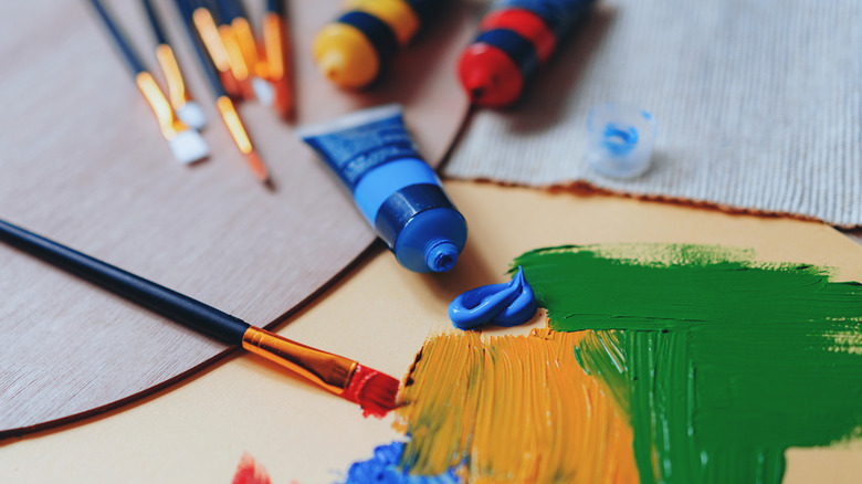 A collection of paint brushes and paints are scattered on a table