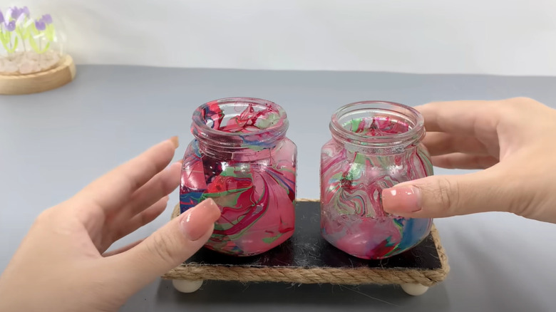 Close-up shot of a woman decorating her mini glass jar planters with paint.