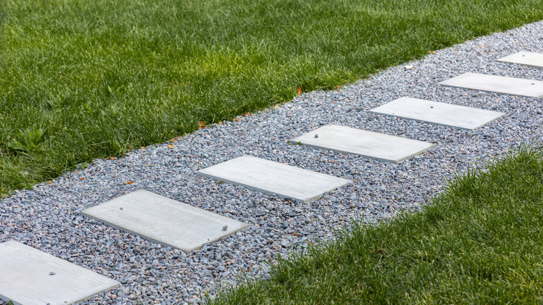 A paver path with gravel through grassy lawn