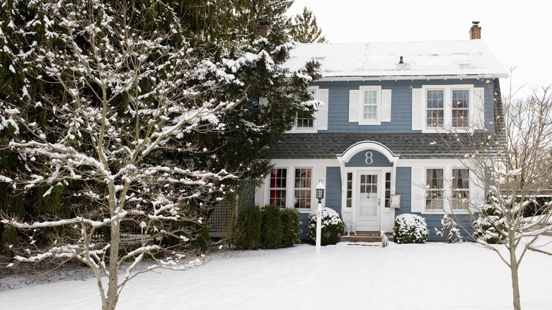 A blue two story house with a snow covered lawn