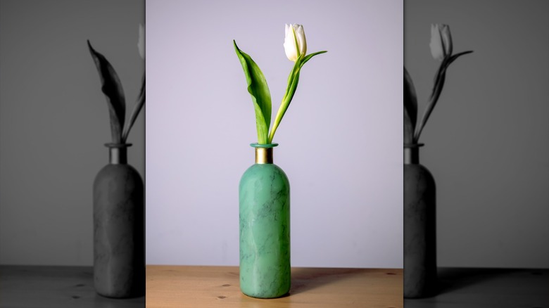 A seafoam green marbled vase holds a single white flower