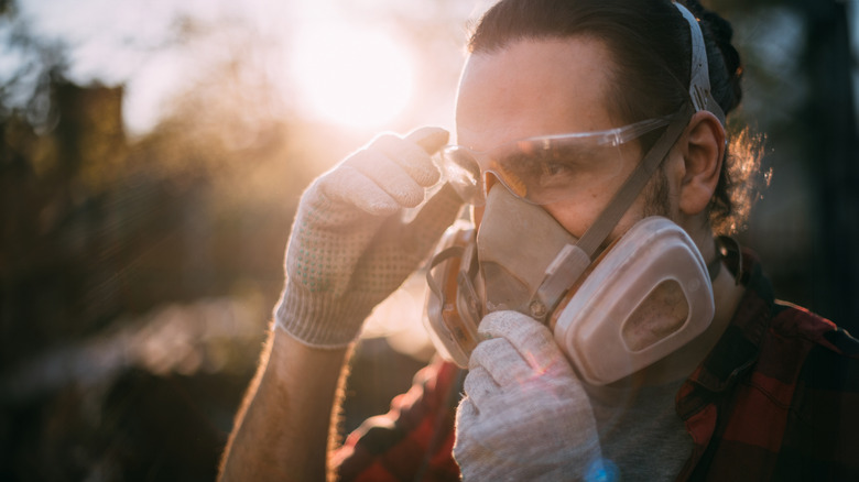 A man wears gloves, a mask, and safety goggles