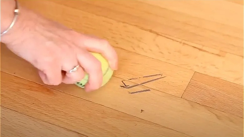 person erasing scuffs with tennis ball