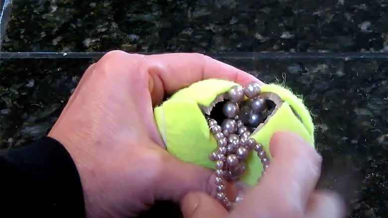 woman putting jewelry inside tennis ball