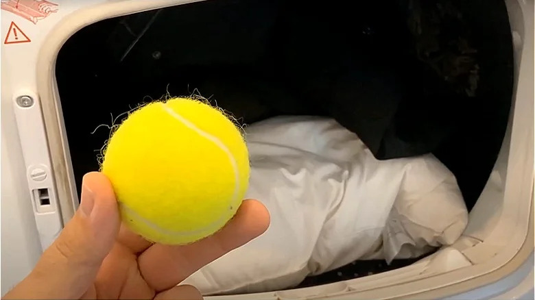 person putting tennis ball in dryer 