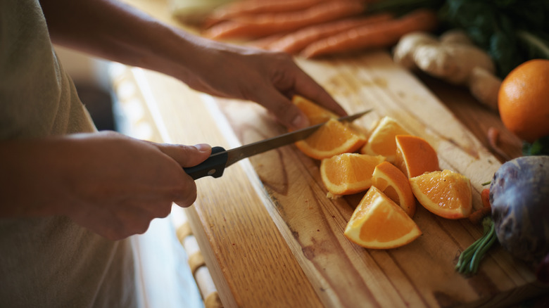 person cutting up an orange