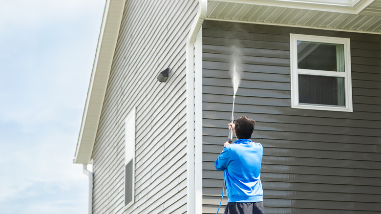 man spraying underneath eaves