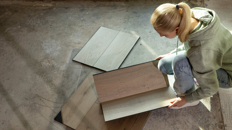 Woman comparing hardwood flooring samples on concrete floor