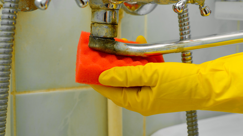 Hand scrubbing rust with sponge