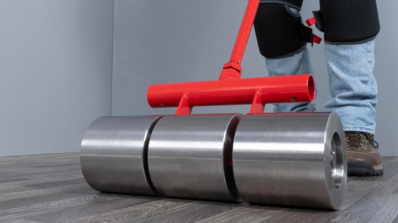 Heavy floor roller going over a wood-style linoleum floor