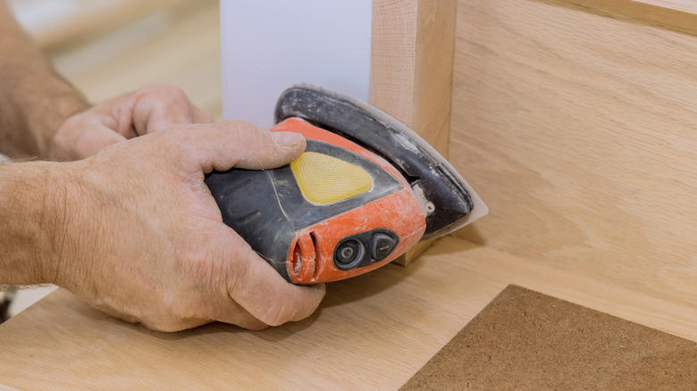 Person sanding stair risers with sander