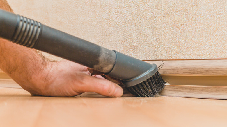 Vacuuming baseboards with brush 