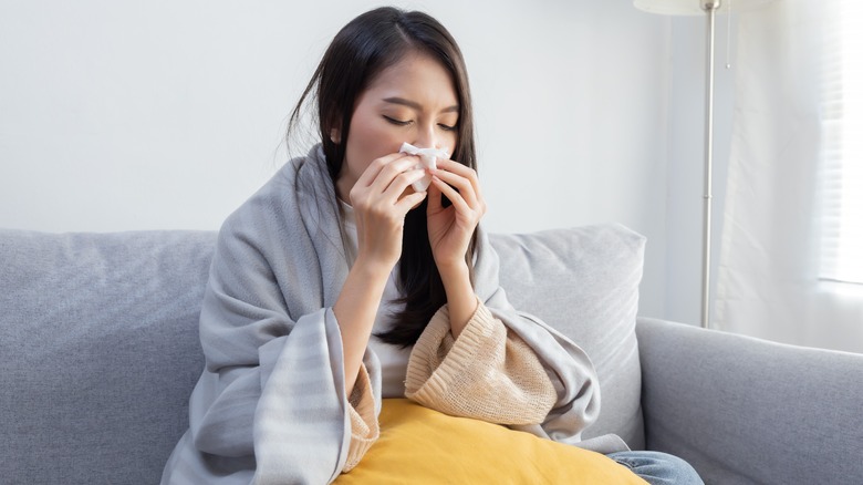 Woman experiencing allergies on couch