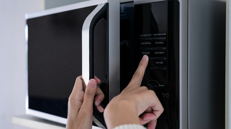 Person pressing buttons on microwave