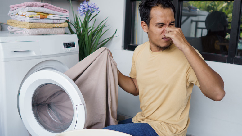 man putting clothes in smelly machine