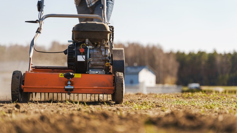 Person using grass aerator in field