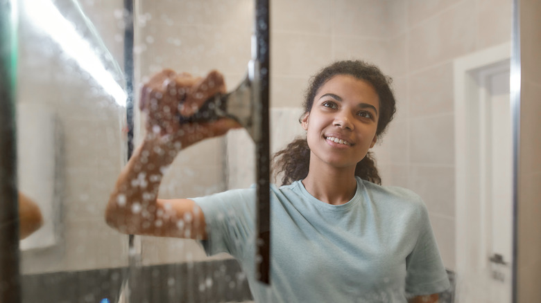 woman squeegeeing glass shower door 