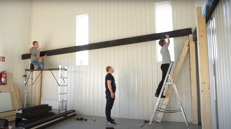 People lifting a support beam into place for a garage loft