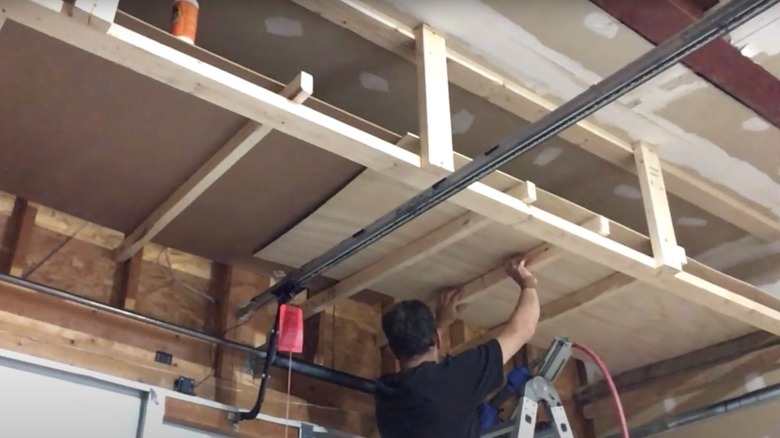 Person lifting plywood sheets into place for a garage loft floor