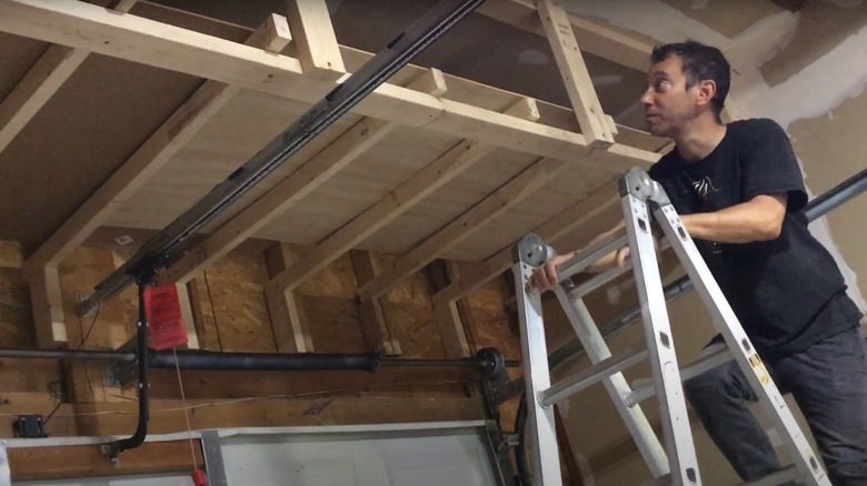 A person standing on a ladder near the garage loft